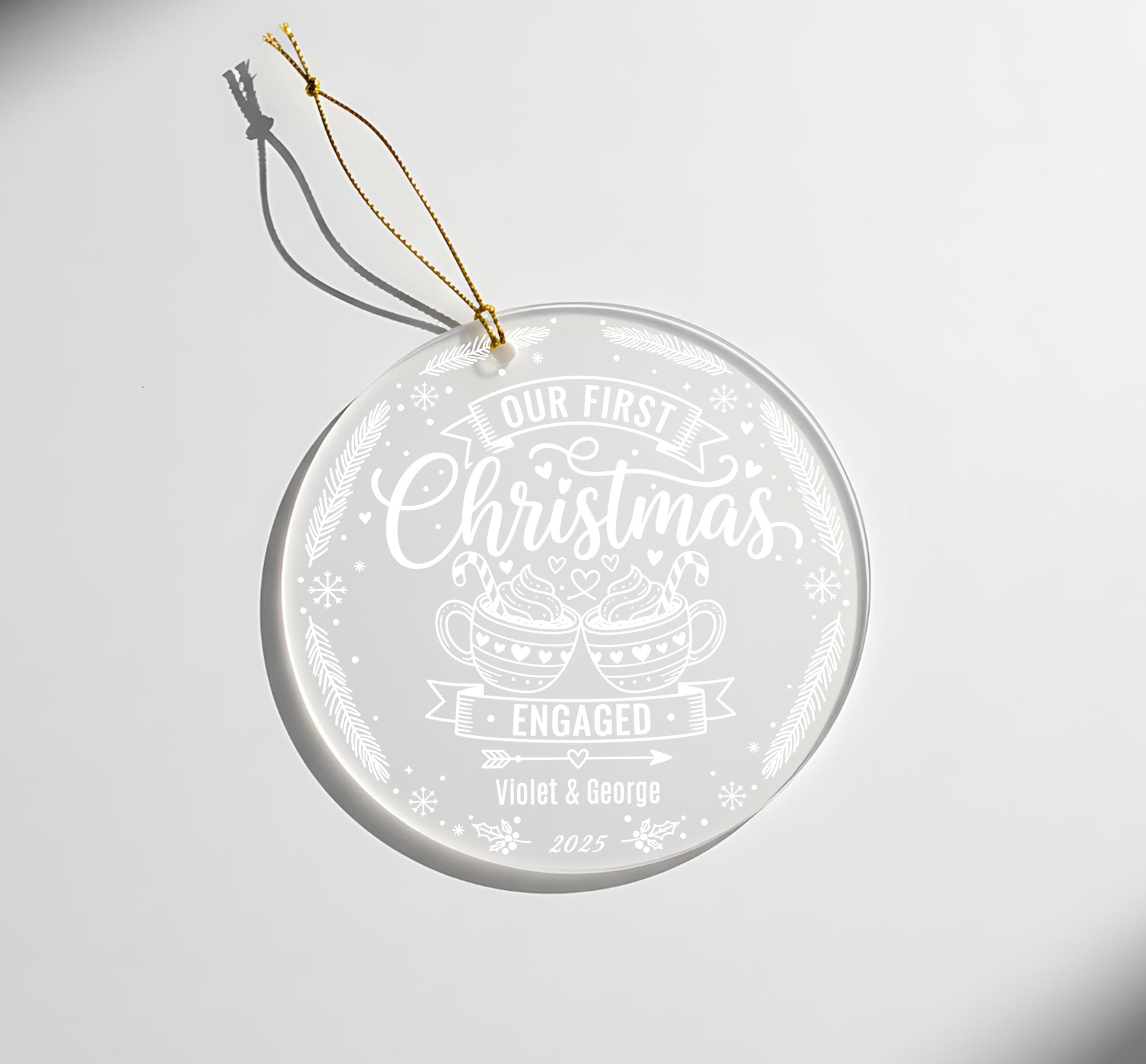 A clear ornament with a white design and text, hanging on a string.