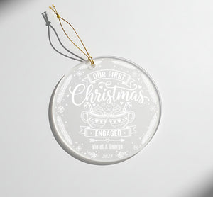 A clear ornament with a white design and text, hanging on a string.