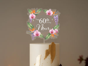 A white cake with a floral topper that says "Happy 60th Birthday Mum" on it.