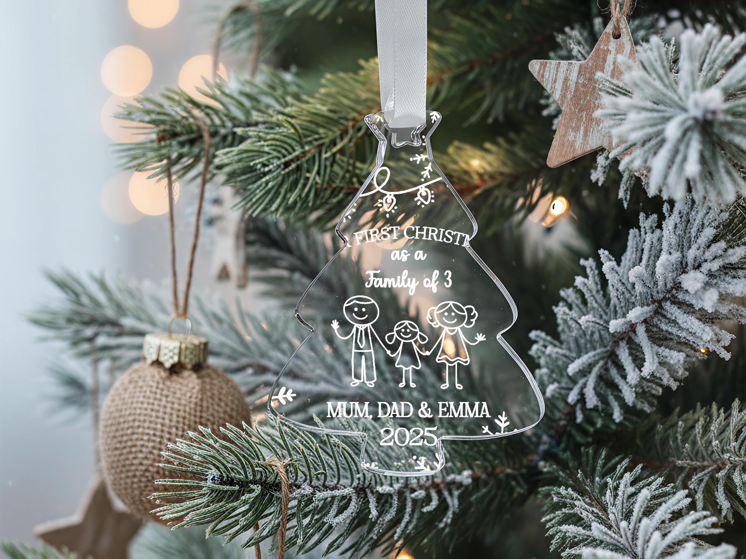 A Christmas tree decorated with ornaments, including a clear ornament shaped like a tree with a message about a family.