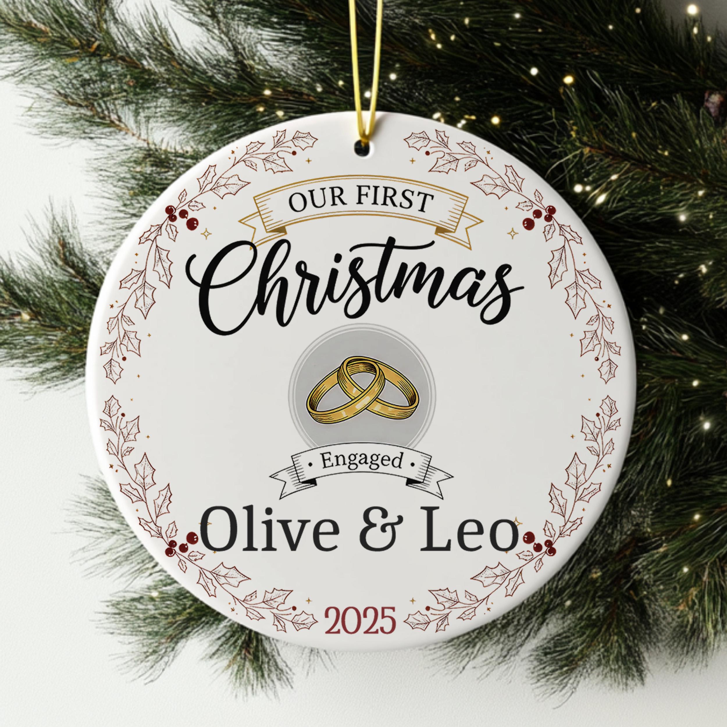 A white Christmas ornament with the text "Our first Christmas" and "Engaged Olive & Leo" printed on it, along with a graphic of a ring and holly leaves.