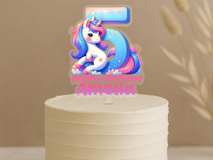 Custom fairytale unicorn cake topper featuring number 5 with magical rainbow unicorn and personalised name Amelia on cream cake