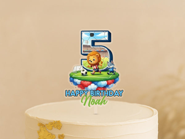 A birthday cake topper with a cartoon lion and soccer ball, along with the text "Happy Birthday Noah".