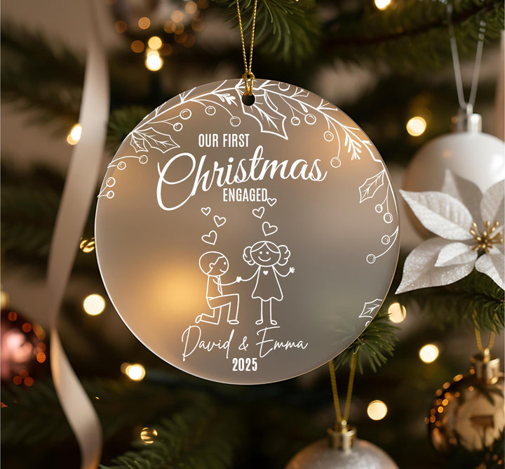 A Christmas ornament with the text &quot;Our first Christmas engaged&quot; and a drawing of a couple embracing.