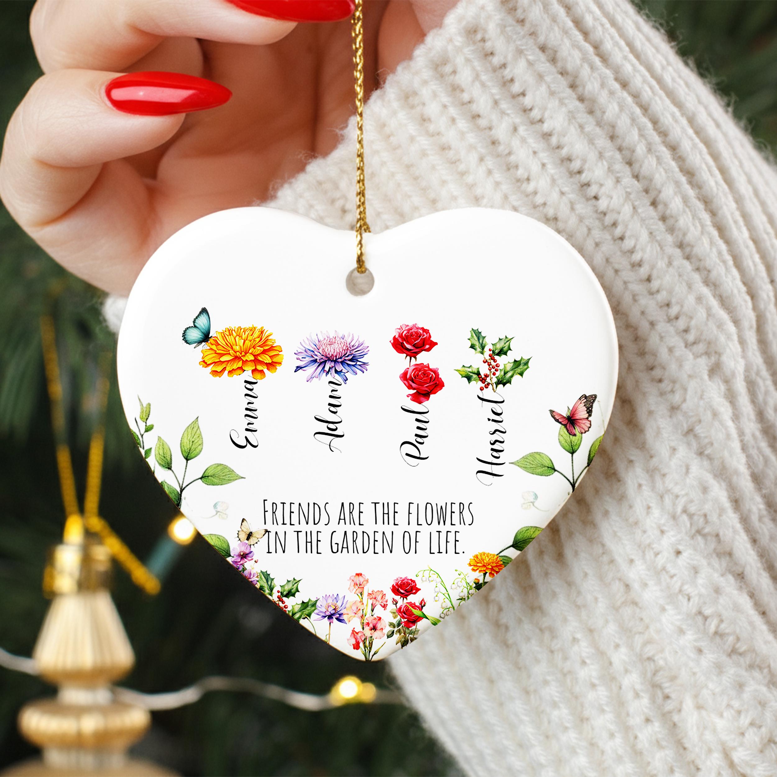 A heart-shaped ornament with floral designs and the text "Friends are the flowers in the garden of life" hanging from a person's arm.