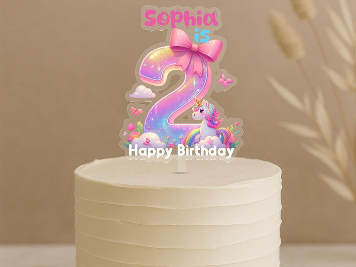 Personalised unicorn birthday cake topper showing rainbow gradient number 2 with cute unicorn, bow and custom name Sophia on white cake
