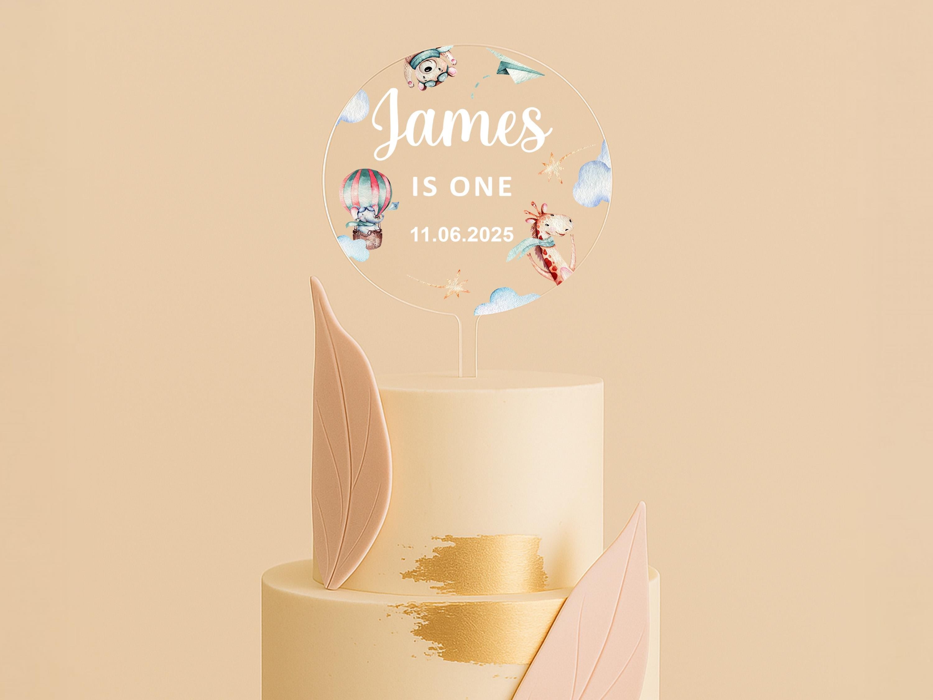 a three tiered cake with a topper that says james is one
