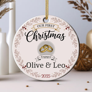 A Christmas ornament with the text "Our first Christmas" and "Engaged Olive & Leo" along with a graphic of a couple's wedding rings.
