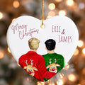 A heart-shaped ornament with two people wearing Christmas sweaters with reindeer designs. The ornament has a "Merry Christmas" message and the names "ERIC & JAMES" written on it.