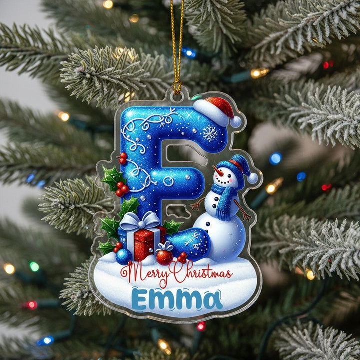 A clear ornament with a snowman and presents, hanging on a Christmas tree.