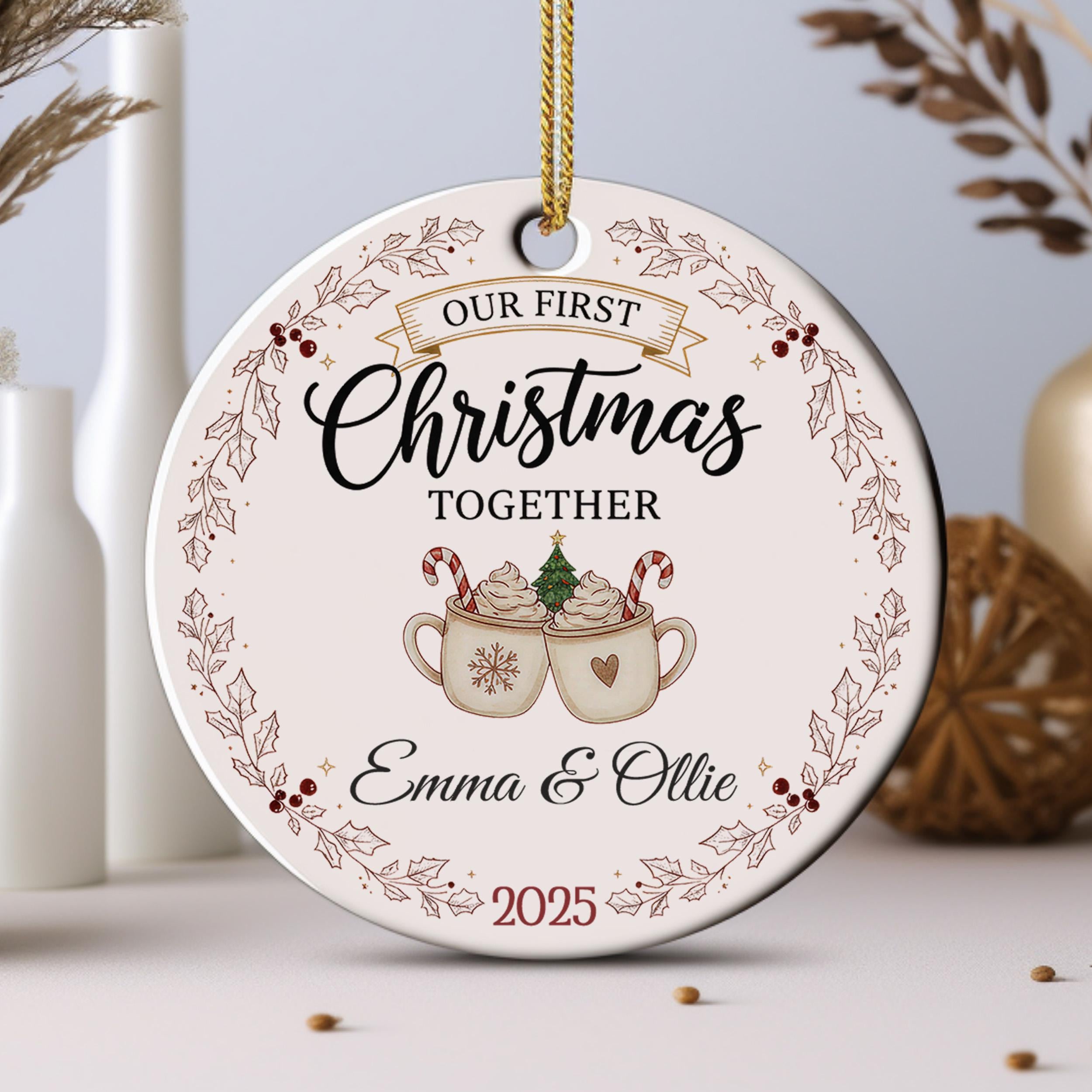 A Christmas ornament with the text "Our first Christmas together" and an illustration of two mugs with hot chocolate and candy canes.