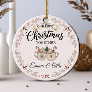 A Christmas ornament with the text "Our first Christmas together" and an illustration of two mugs with hot chocolate and candy canes.