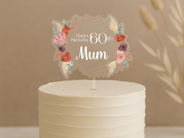 Personalised 60th birthday cake topper featuring boho diamond frame with coral roses, pink flowers, pampas grass and custom name Mum on white celebration cake
