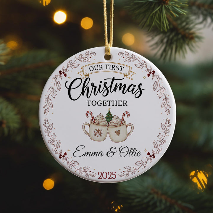 A white ornament with a festive design hangs on a Christmas tree, surrounded by pine branches.