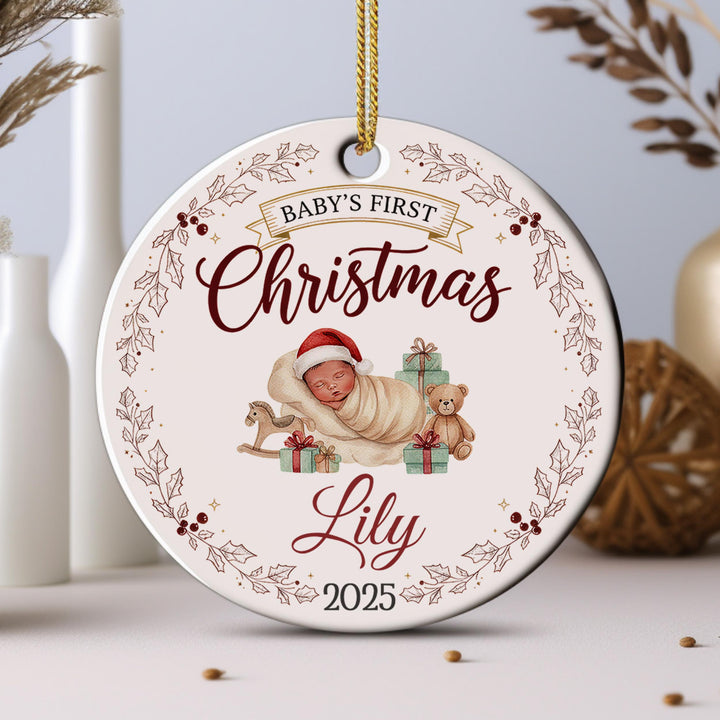 A white ornament with a baby and Christmas-themed decorations, including a teddy bear and presents.