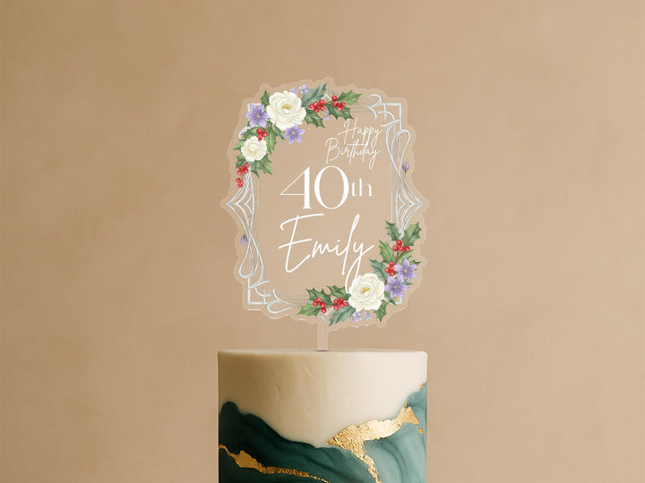 A birthday cake with a clear topper that says &quot;Happy Birthday Emily&quot; surrounded by a floral design.