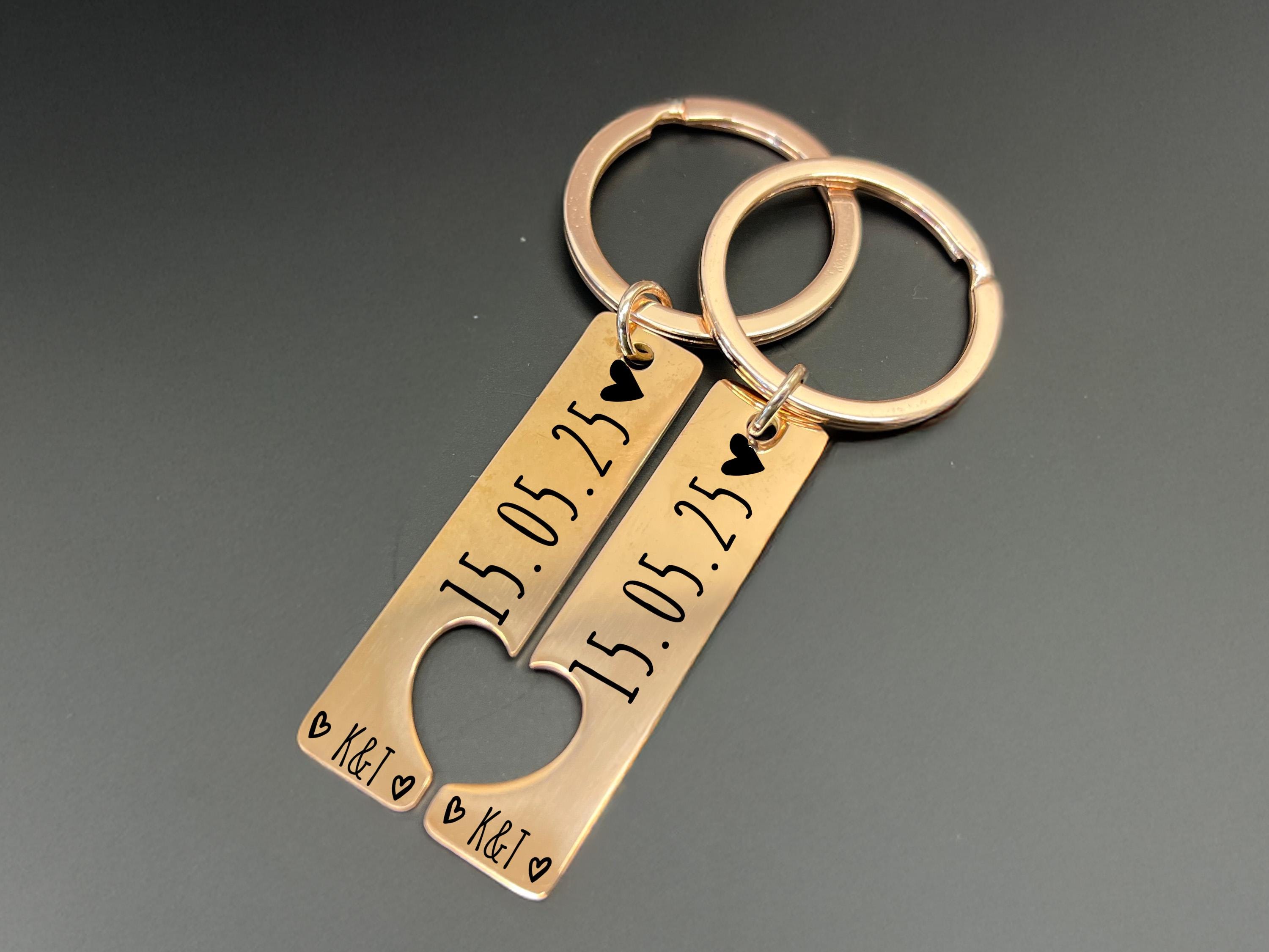 Personalised couple keyring set with engraved date and initials, two matching keychains in silver finish, interlocking heart design.