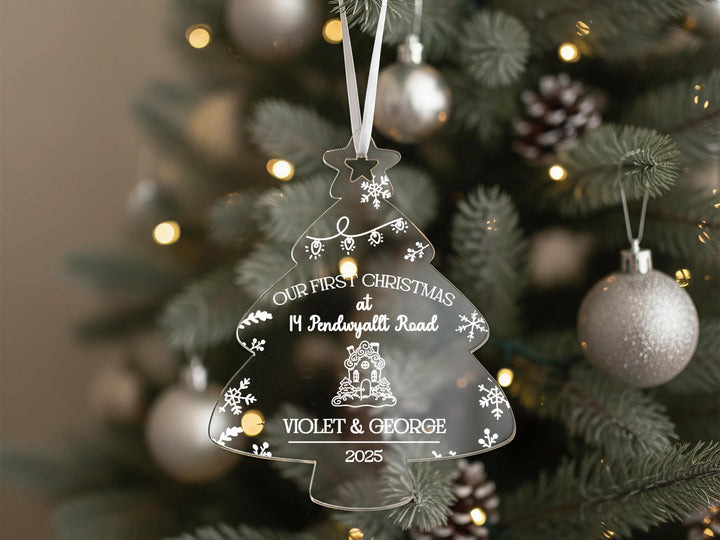 A clear ornament hanging from a Christmas tree, displaying a personalized message.