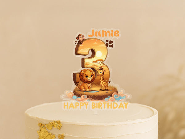 Custom jungle animal cake topper showing number 3 with lion, giraffe and monkey on African sunset landscape, personalised with name Jamie, on white birthday cakeRetry