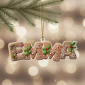 A decorative ornament shaped like the name "Emma" made of gingerbread cookies, hanging from a string.