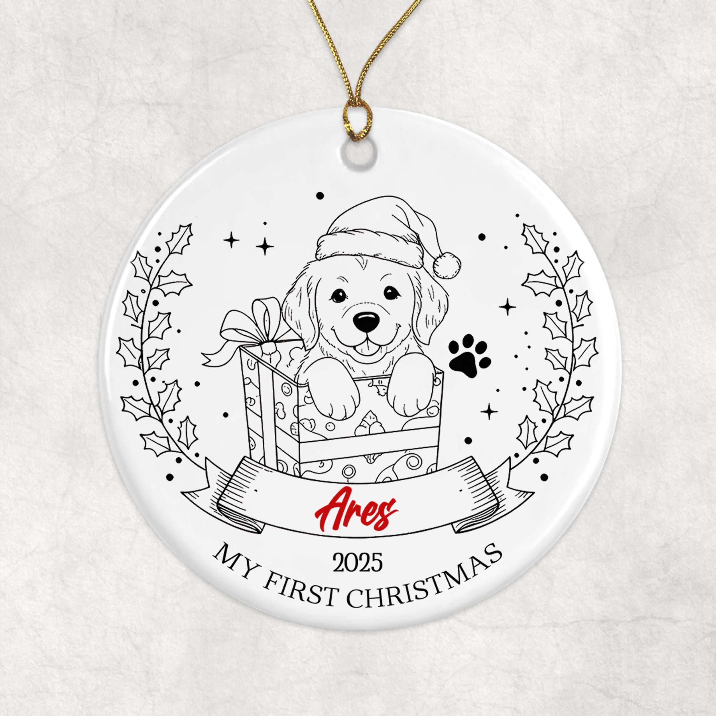 A white ornament with a black and white illustration of a dog wearing a Santa hat, holding a gift box, and surrounded by holly leaves and stars.