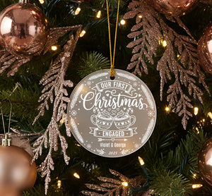 A Christmas tree decorated with ornaments, including a large ornament that says "Our first Christmas" and "Engaged" in white text.