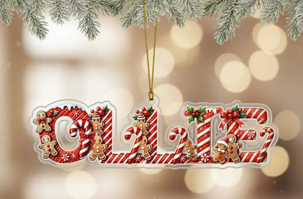 A clear ornament shaped like the word &quot;Ollie&quot; made of candy canes, gingerbread men, and other festive decorations.