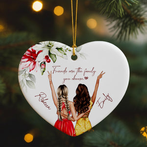 A heart-shaped ornament featuring two women with braided hair, wearing red and yellow dresses, and the text "Friends are the family you choose" written on it.