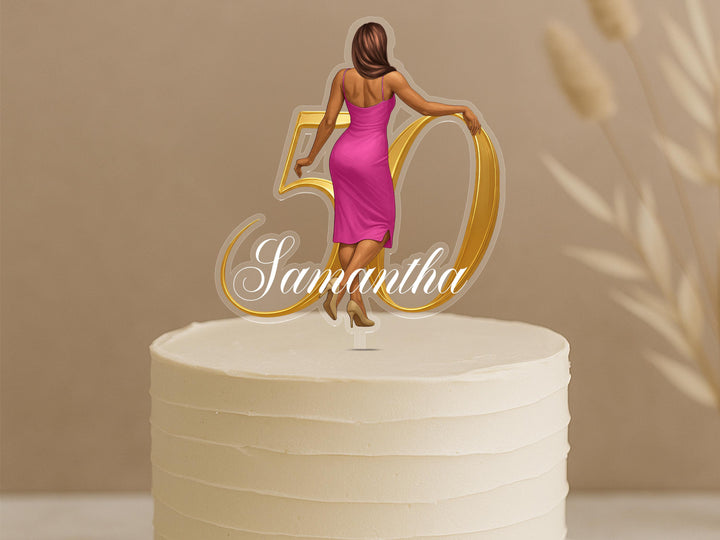 A cake topper with a woman in a pink dress and the number 50 on it.