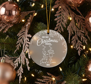 A Christmas tree decorated with ornaments, including a round ornament with a message that reads "Our first Christmas engaged David & Emma 2015".