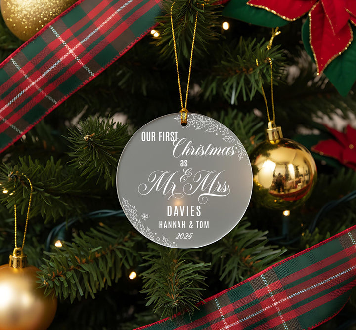 A Christmas tree decorated with ornaments, including a clear ornament that reads &quot;Our first Christmas as Mr & Mrs Davies Hannah & Tom 20.25&quot;.