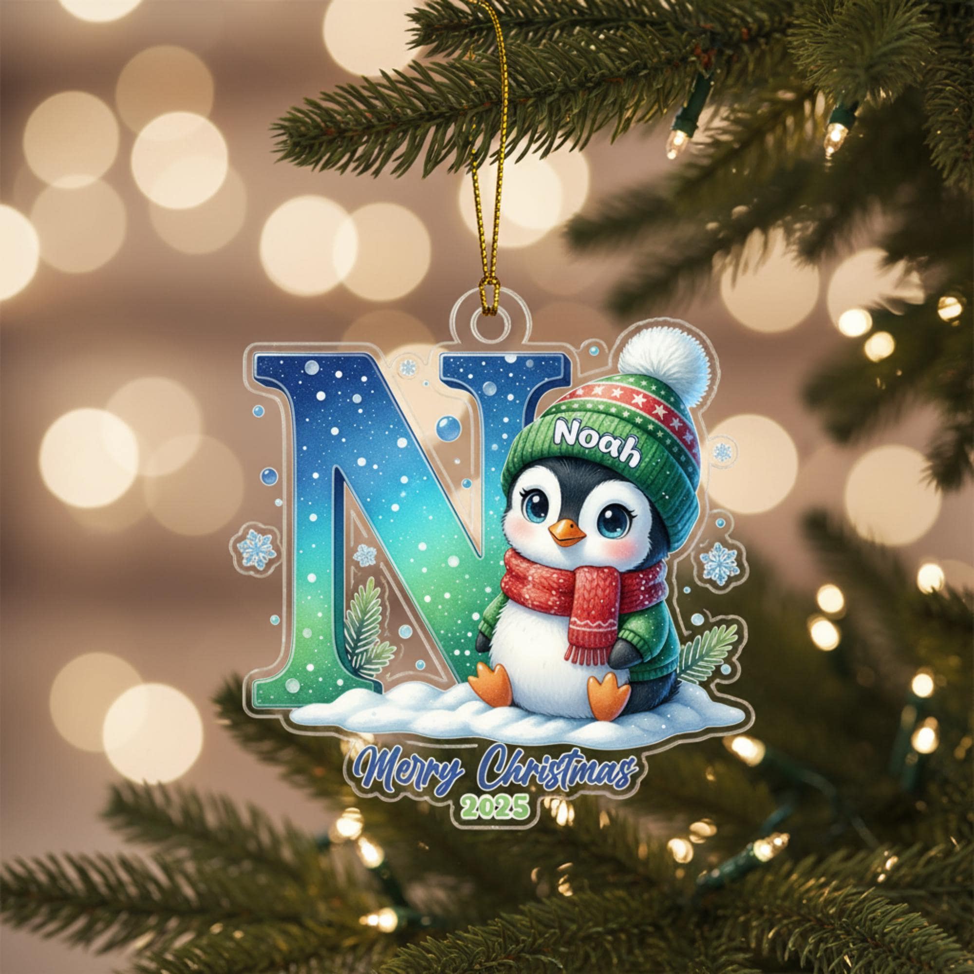 A Christmas ornament featuring a penguin wearing a red scarf and hat, with the name "Noah" written on it, hanging on a tree branch.