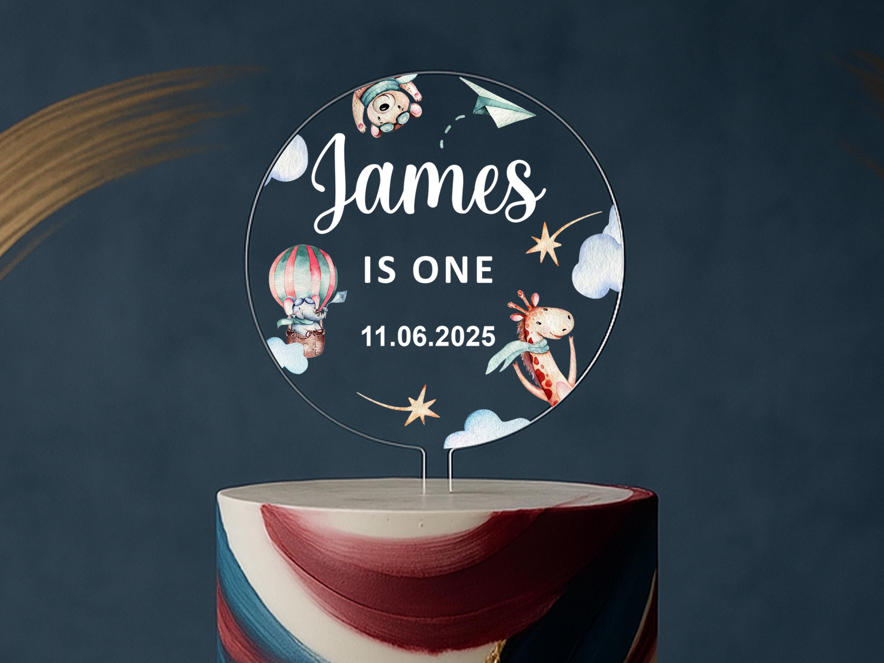 a birthday cake with a topper that says james is one