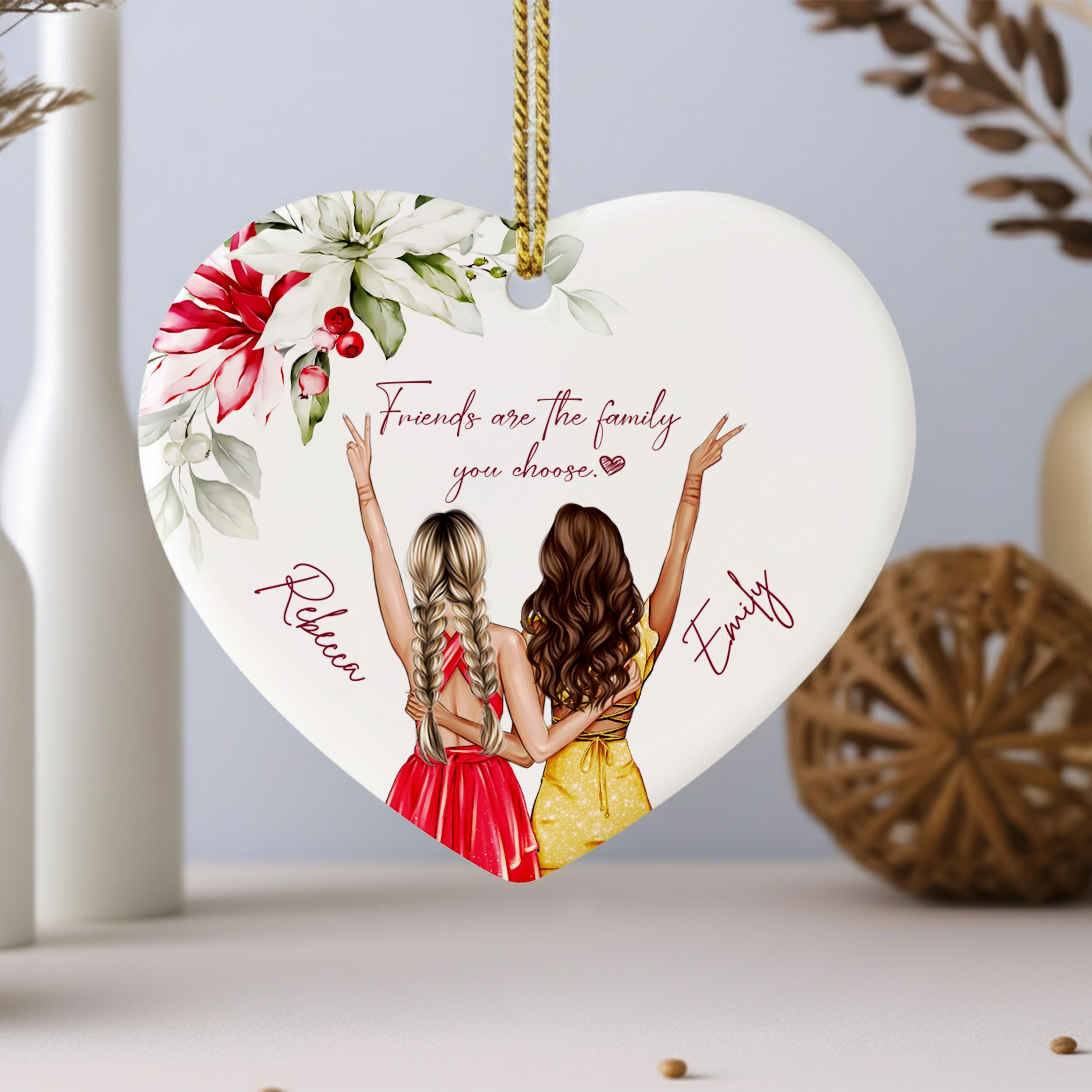 A heart-shaped ornament with two women in colorful dresses, each making a peace sign, and the text "Friends are the family you choose" written above them.