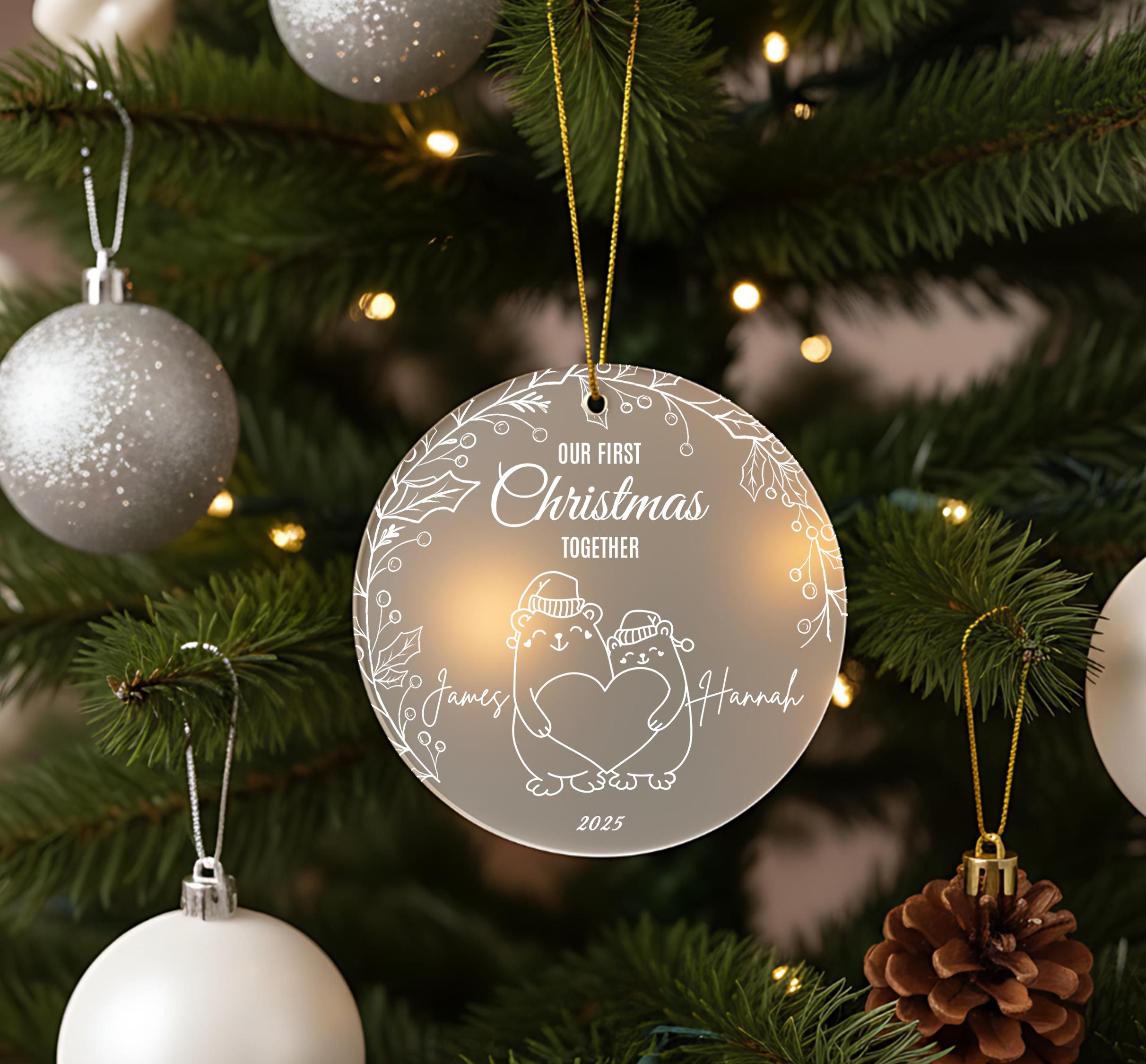 A Christmas tree decorated with ornaments, including a clear ornament with a couple and the text "Our first Christmas together" and "James and Hannah" written on it.
