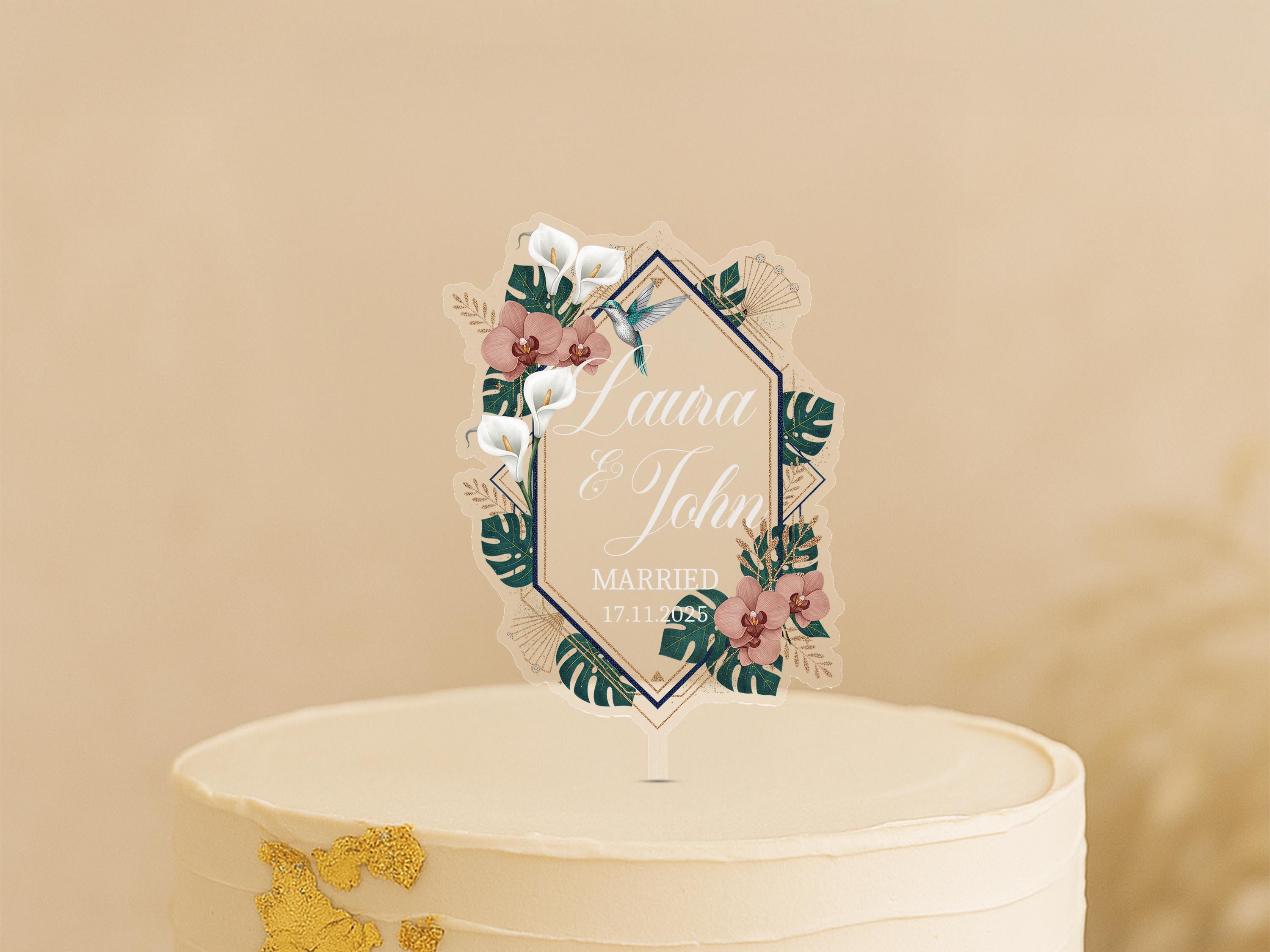 A white wedding cake with a decorative floral topper featuring the names "Lena & John" and the date "MARCH 17, 2020".