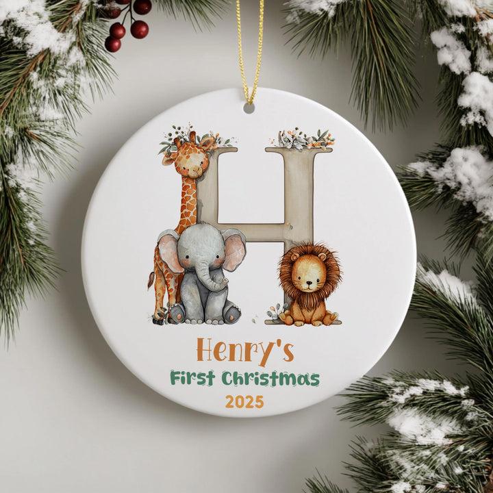 A white ornament with a letter &quot;H&quot; and illustrations of a giraffe, elephant, and lion, hanging on a string.