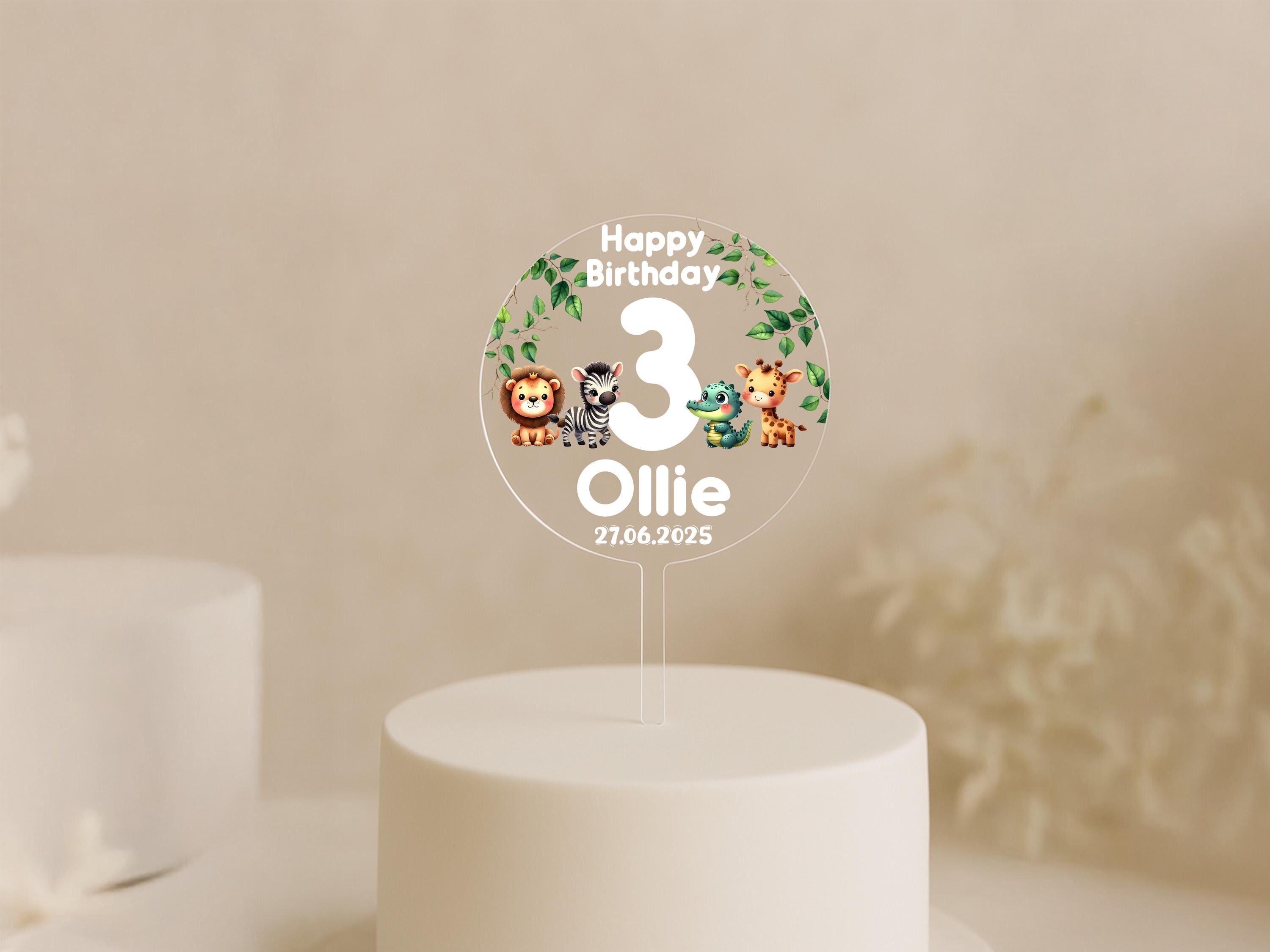 Close-up of safari-themed birthday cake topper with vibrant animal illustrations and custom text.