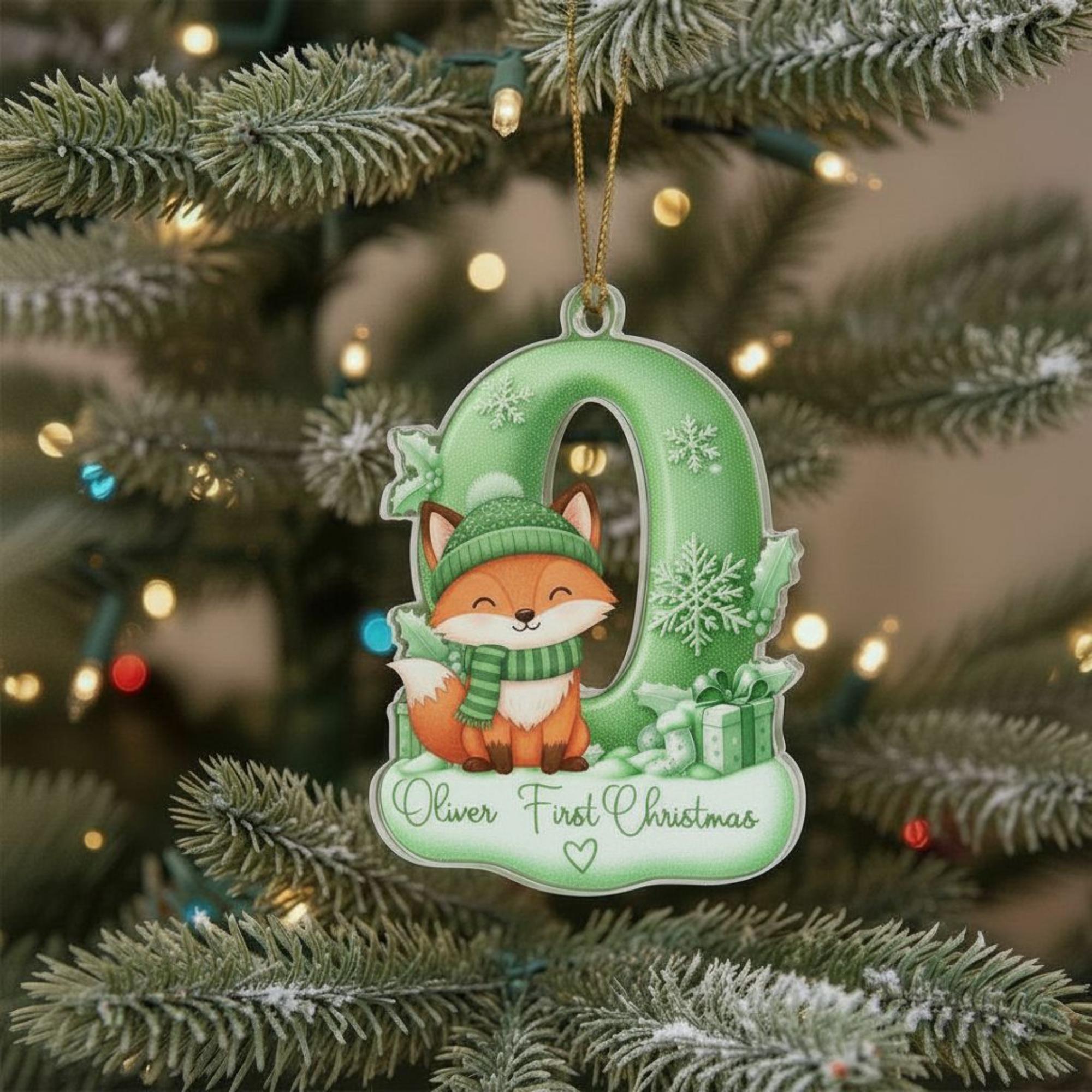 A green ornament shaped like the letter "O" with a cartoon fox wearing a scarf and hat, hanging on a Christmas tree.