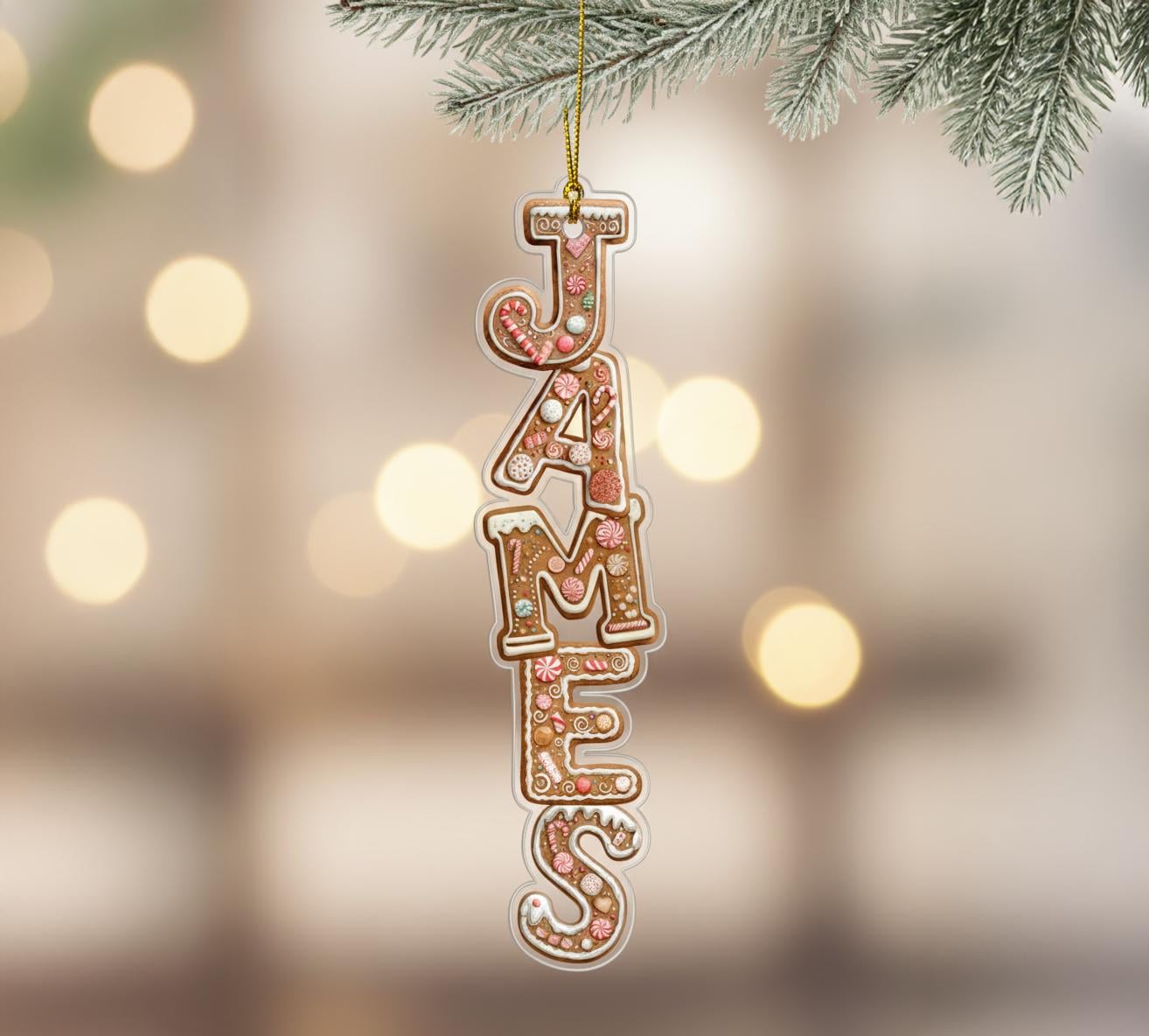 A decorative ornament made of gingerbread letters spelling out the name "JAMES" hanging from a branch of a pine tree.