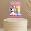 Personalised unicorn first birthday cake topper showing rainbow number 1 with cute unicorn and custom name Olive on white celebration cake