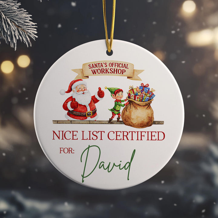 A white ornament with a Santa Claus and an elf, along with a &quot;NICE LIST CERTIFIED FOR: David&quot; inscription.