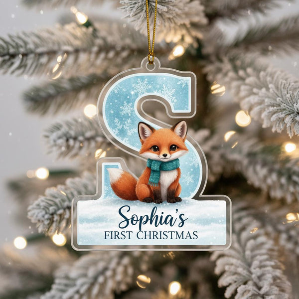 A clear ornament shaped like the letter &#39;S&#39; with a fox sitting on top, hanging on a Christmas tree.