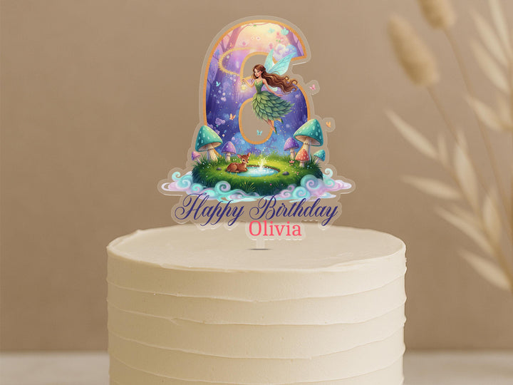 A birthday cake topper featuring a fairy character and a garden scene.