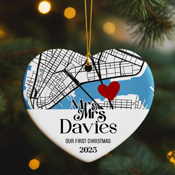 A heart-shaped ornament with a map of a city and a red heart symbol, hanging on a Christmas tree.