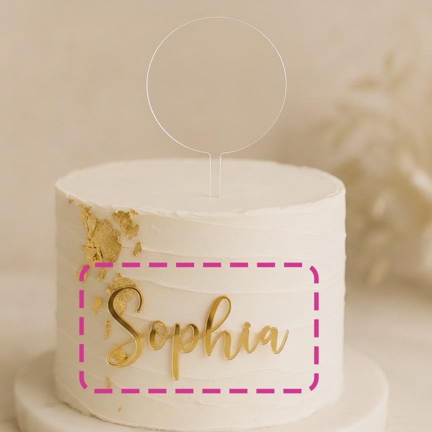 A white cake with gold frosting and the name "Sophia" written on it.