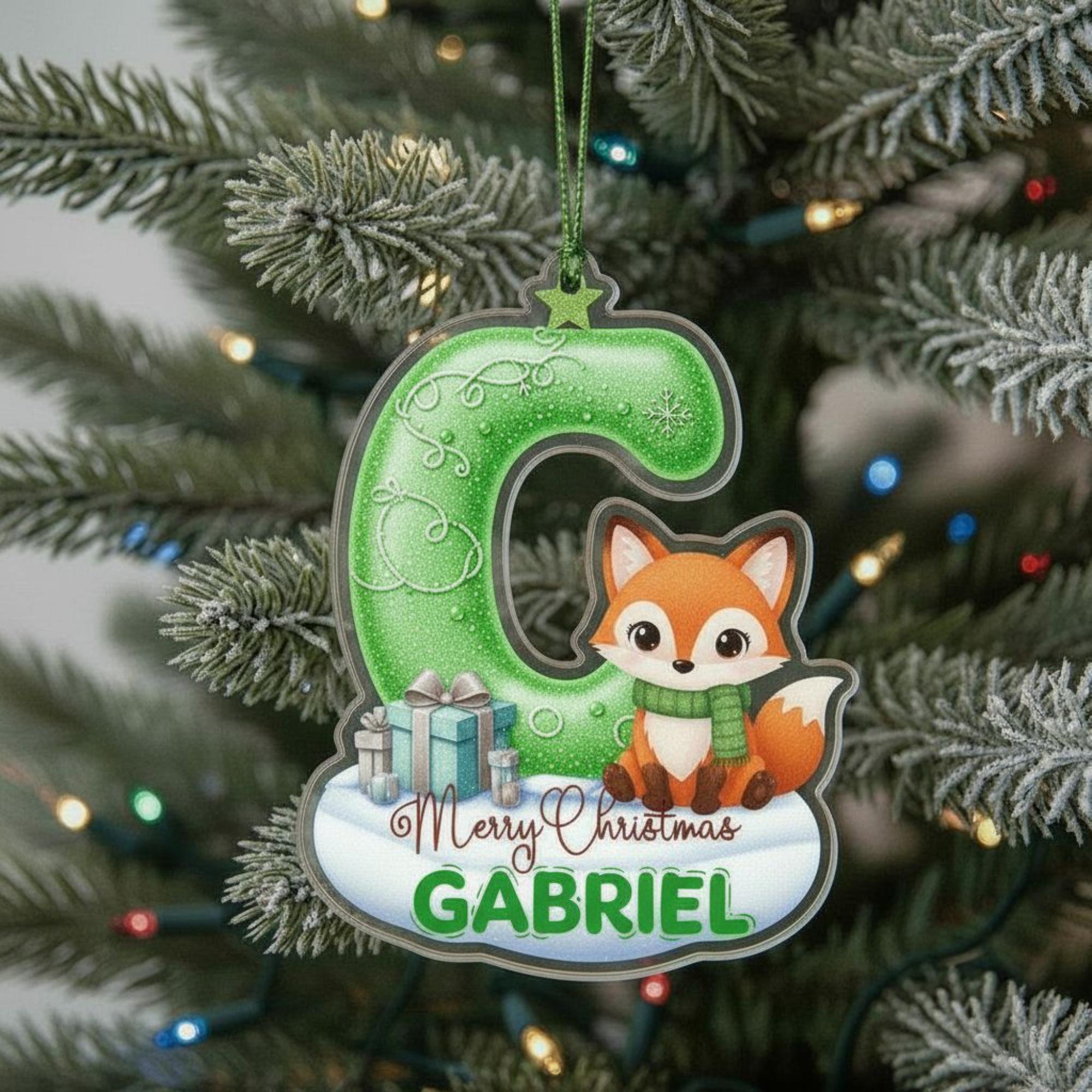 A green ornament shaped like the letter "C" with a cartoon fox sitting on top of it, hanging on a Christmas tree.