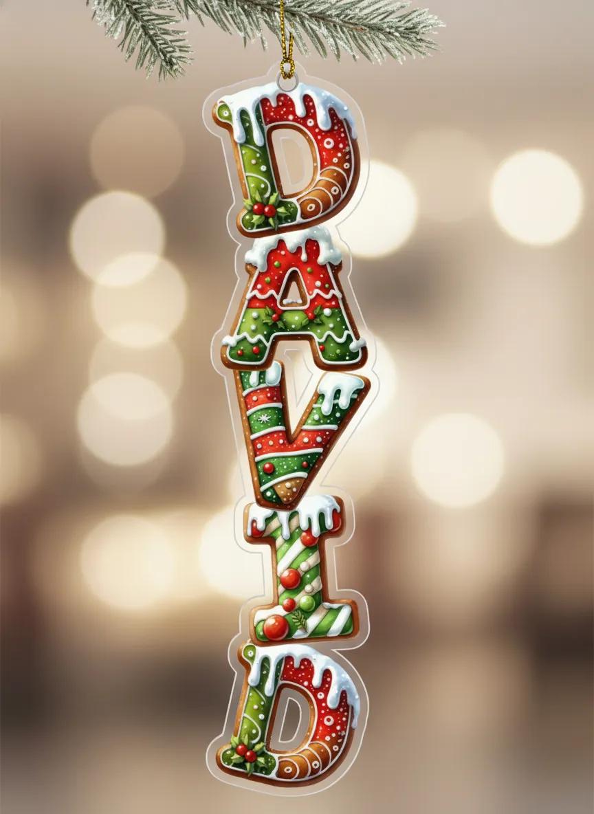 A Christmas ornament shaped like the word "DAVID" made of colorful candy pieces, hanging on a branch with a blurred background.