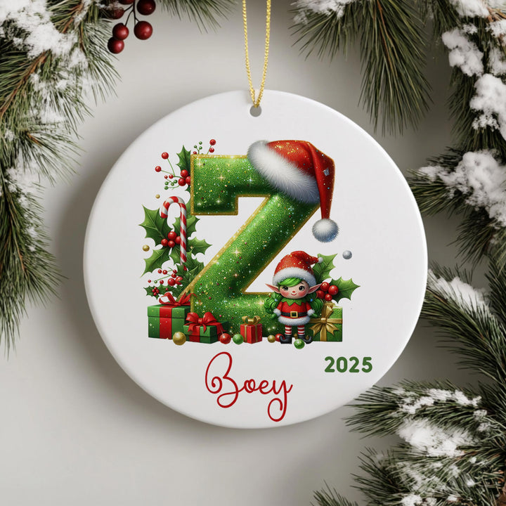 A white ornament with a green letter &quot;Z&quot; and a small elf wearing a Santa hat, surrounded by Christmas decorations such as presents and holly leaves.