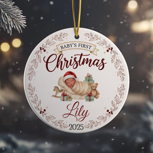 A white ornament with a baby and Christmas-themed decorations hanging from a string.